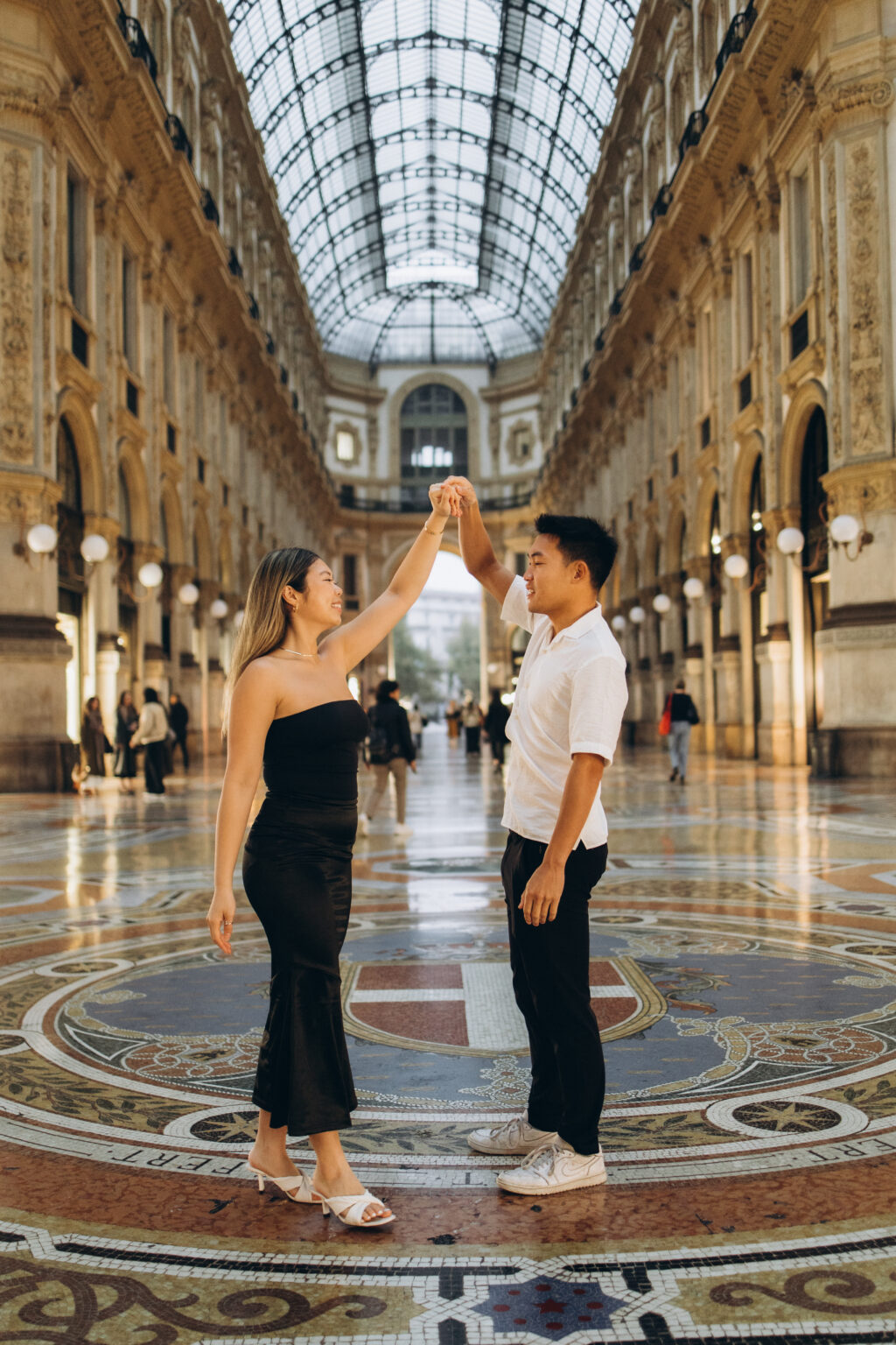 A couple dancing hand in hand under the glass dome of Galleria Vittorio Emanuele II in Milan
