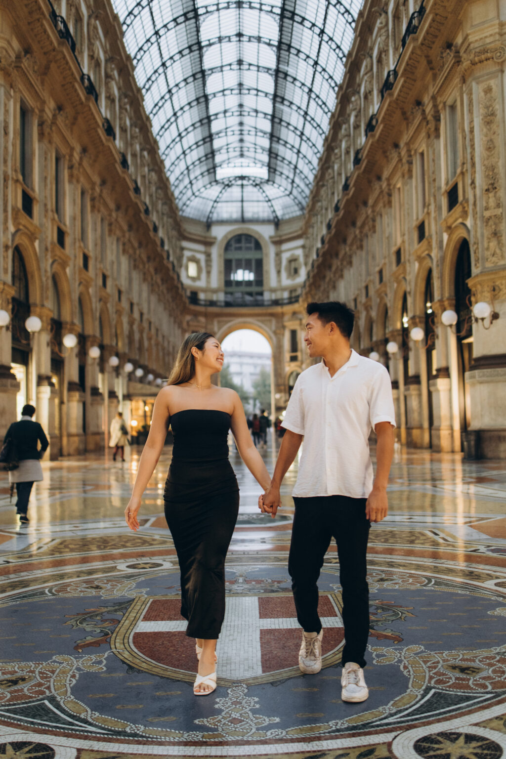 Couple walking hand in hand across the mosaic floor of the Galleria Vittorio Emanuele II, Milan