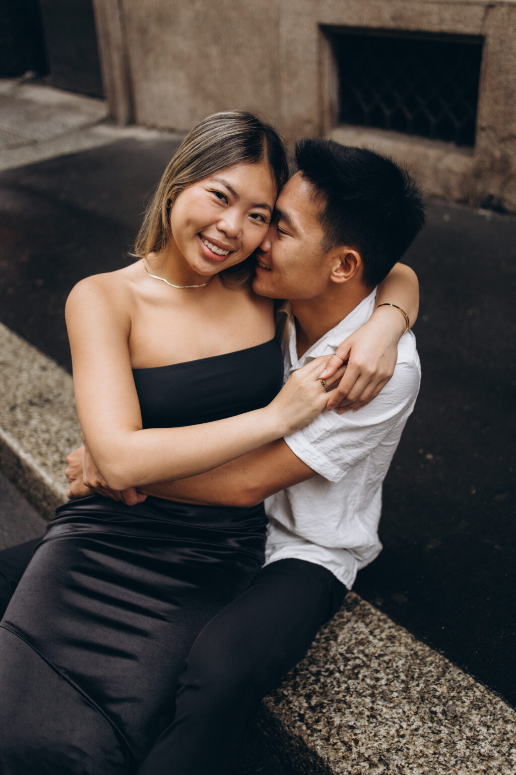 Couple embracing on a stone ledge during an intimate couples photoshoot in Milan