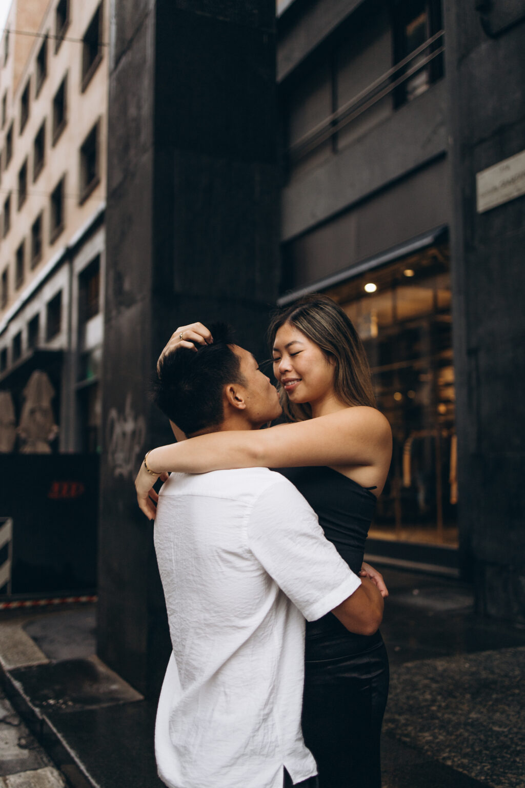 A couple embracing tenderly on a moody city street, arms wrapped around each other in a quiet intimate moment