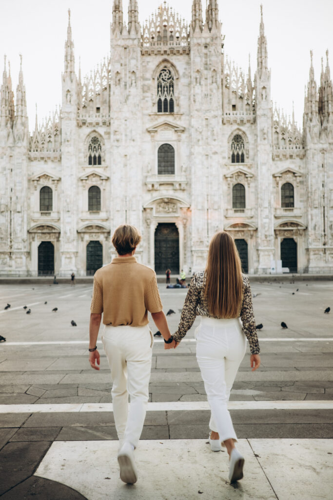 A couple holding hands and walking toward Milan Cathedral across the empty Piazza del Duomo Few images feel as romantic as a couple strolling hand in hand toward the great marble facade of the Duomo, the square quiet and glowing just for them. I photograph couples across Milan and on Lake Como, and travel throughout Italy for private sessions. Looking to hire a couple photographer in Milan? This is the dreamy, cinematic mood I love to create.