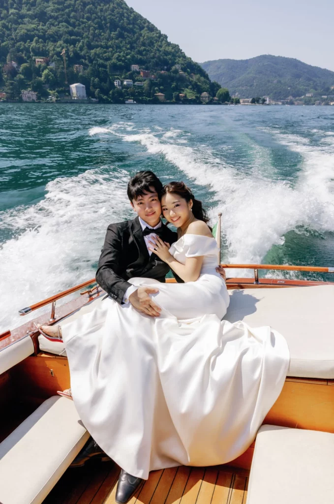 Newlyweds embracing on a classic wooden boat crossing Lake Como