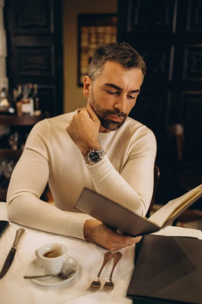Man in a cream sweater reading in a Milan café