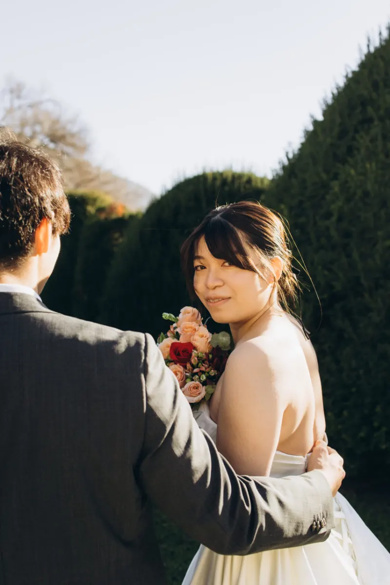 Bride glancing back over the groom’s shoulder in a villa garden on Lake Como