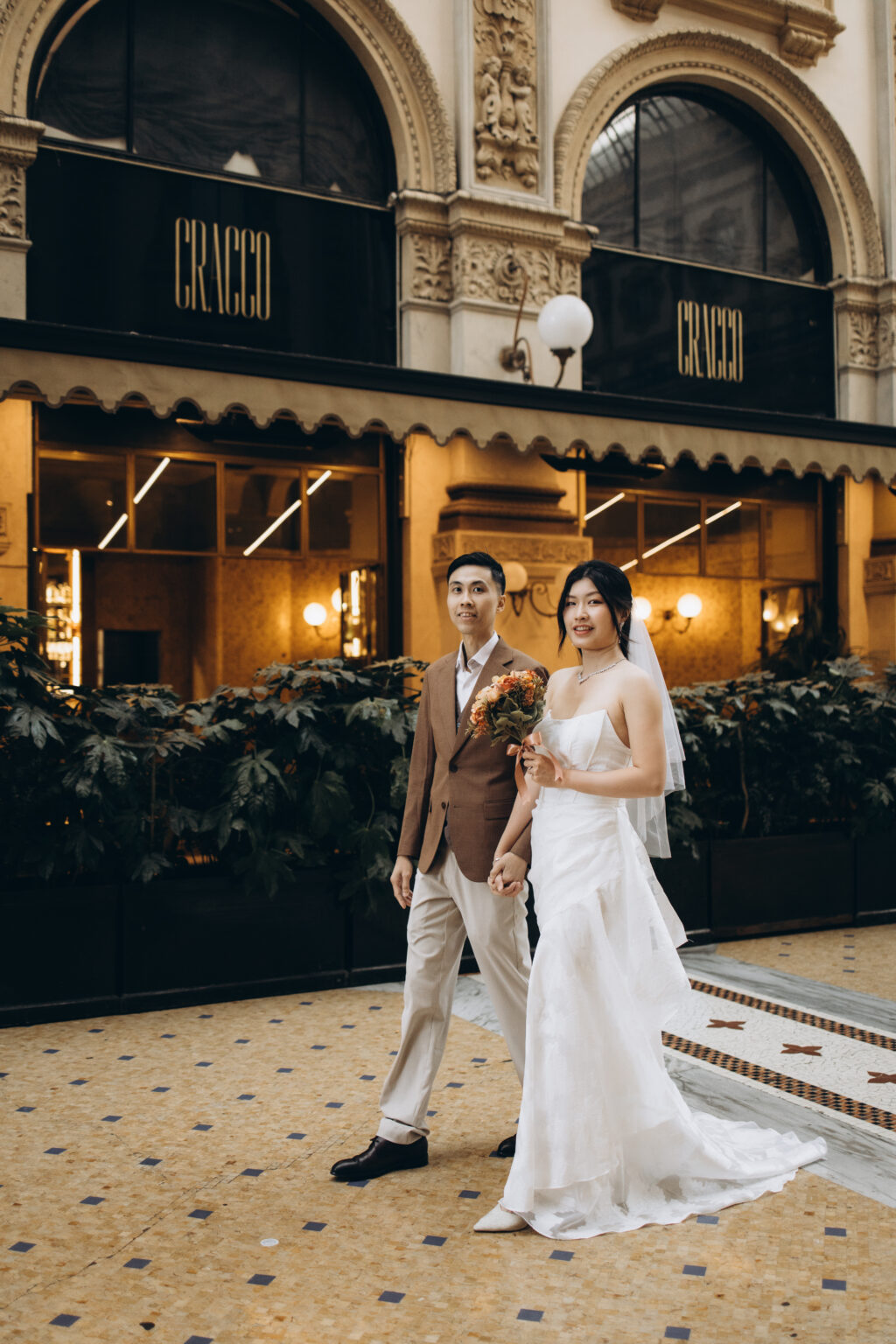 Bride-to-be and groom-to-be walking hand in hand past the Cracco restaurant in the Galleria Vittorio Emanuele II in Milan