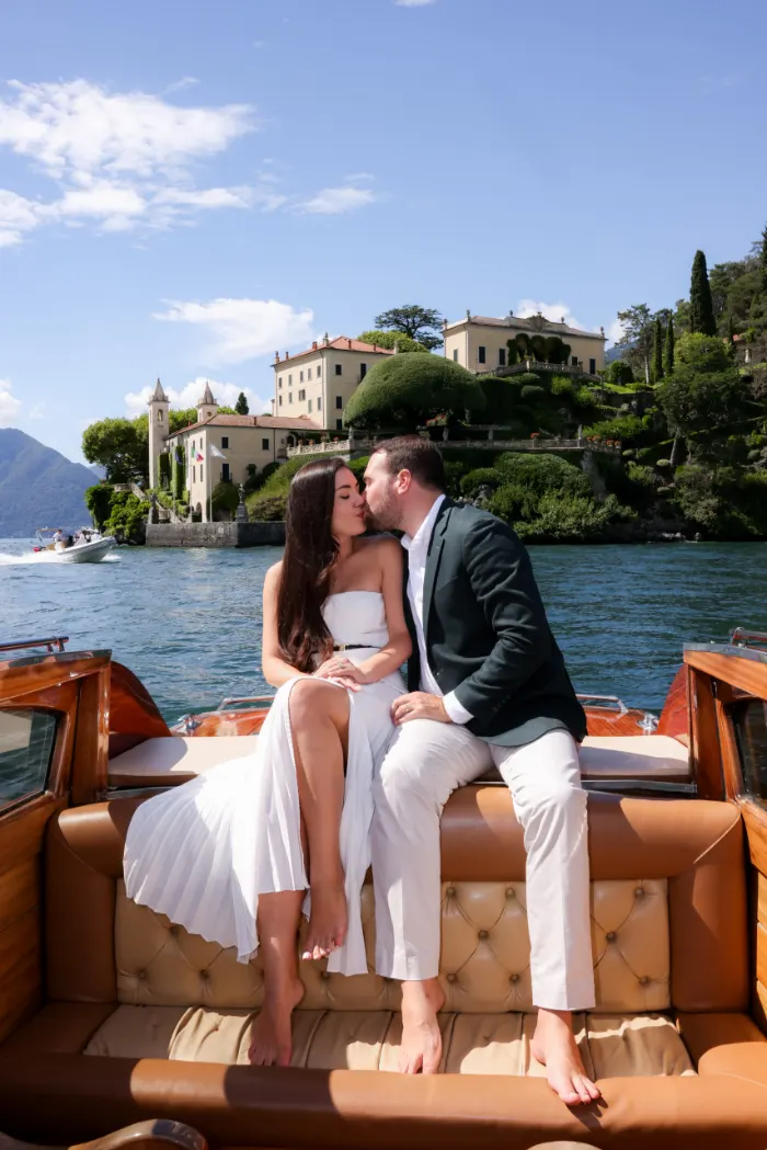 Couple kissing on a boat with the villa behind them