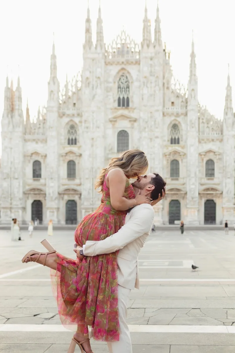 He lifts her for a kiss in the empty Piazza del Duomo, Milan