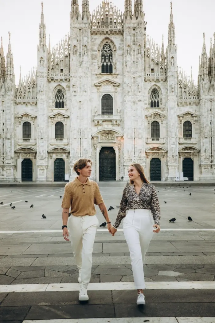 Couple walking hand in hand across Piazza del Duomo in front of Milan Cathedral during a couples photoshoot