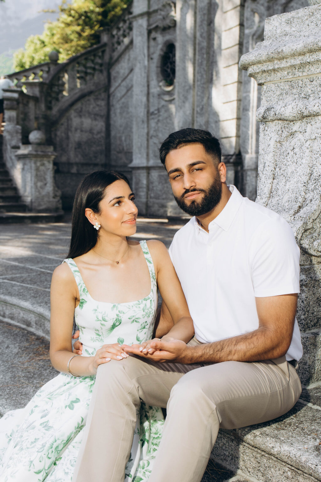 Close portrait of a couple seated against carved granite in Parco Teresio Olivelli, the woman gazing up at the man as he holds her hand