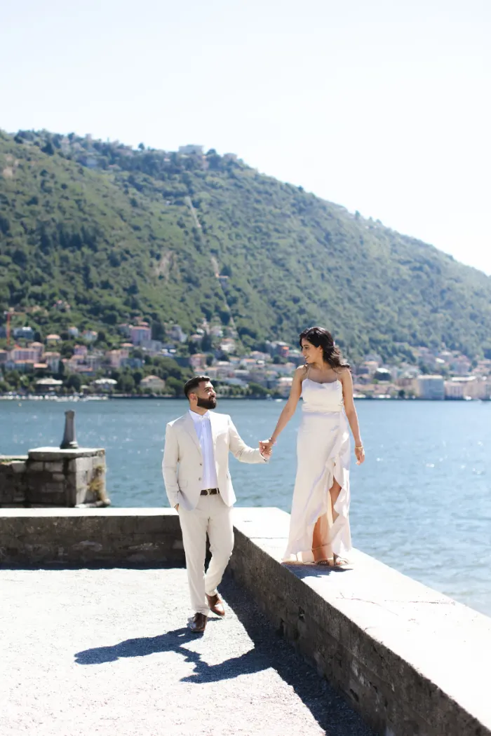 Couple walking hand in hand on the lakefront in Como