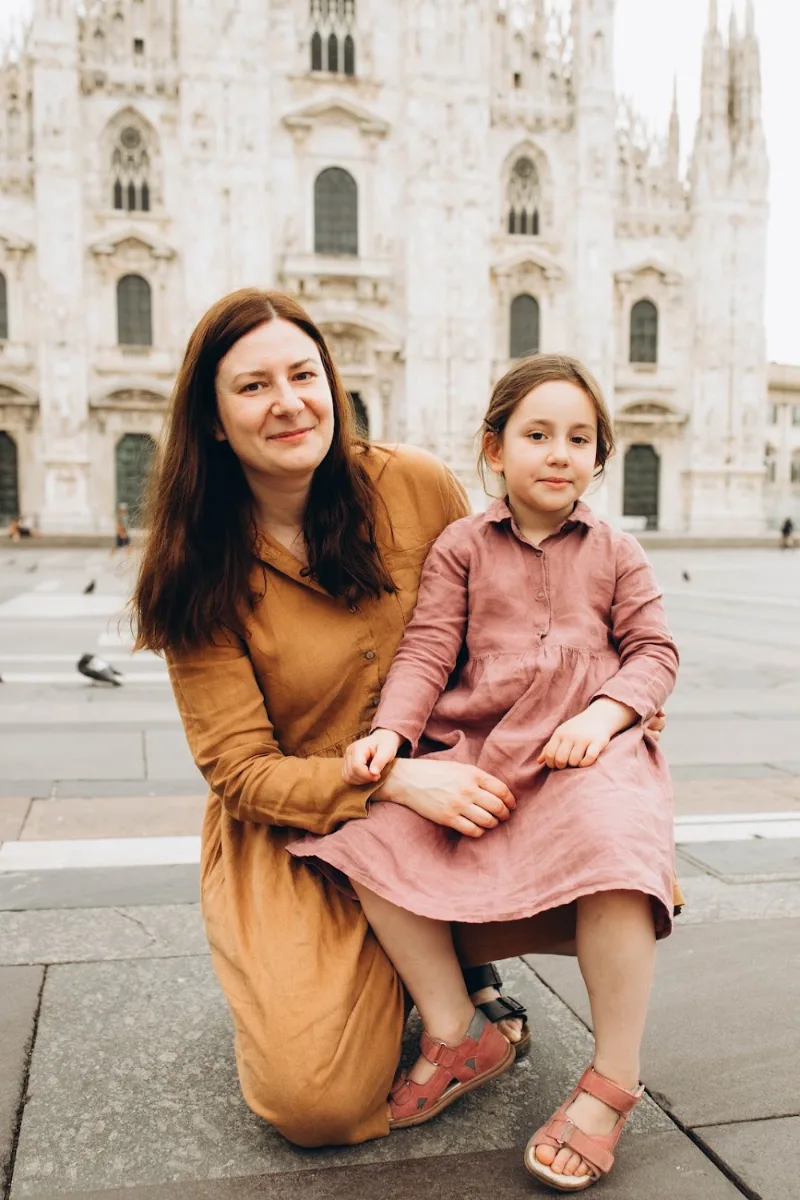 Mother and daughter sitting together in the empty Piazza del Duomo, Milan