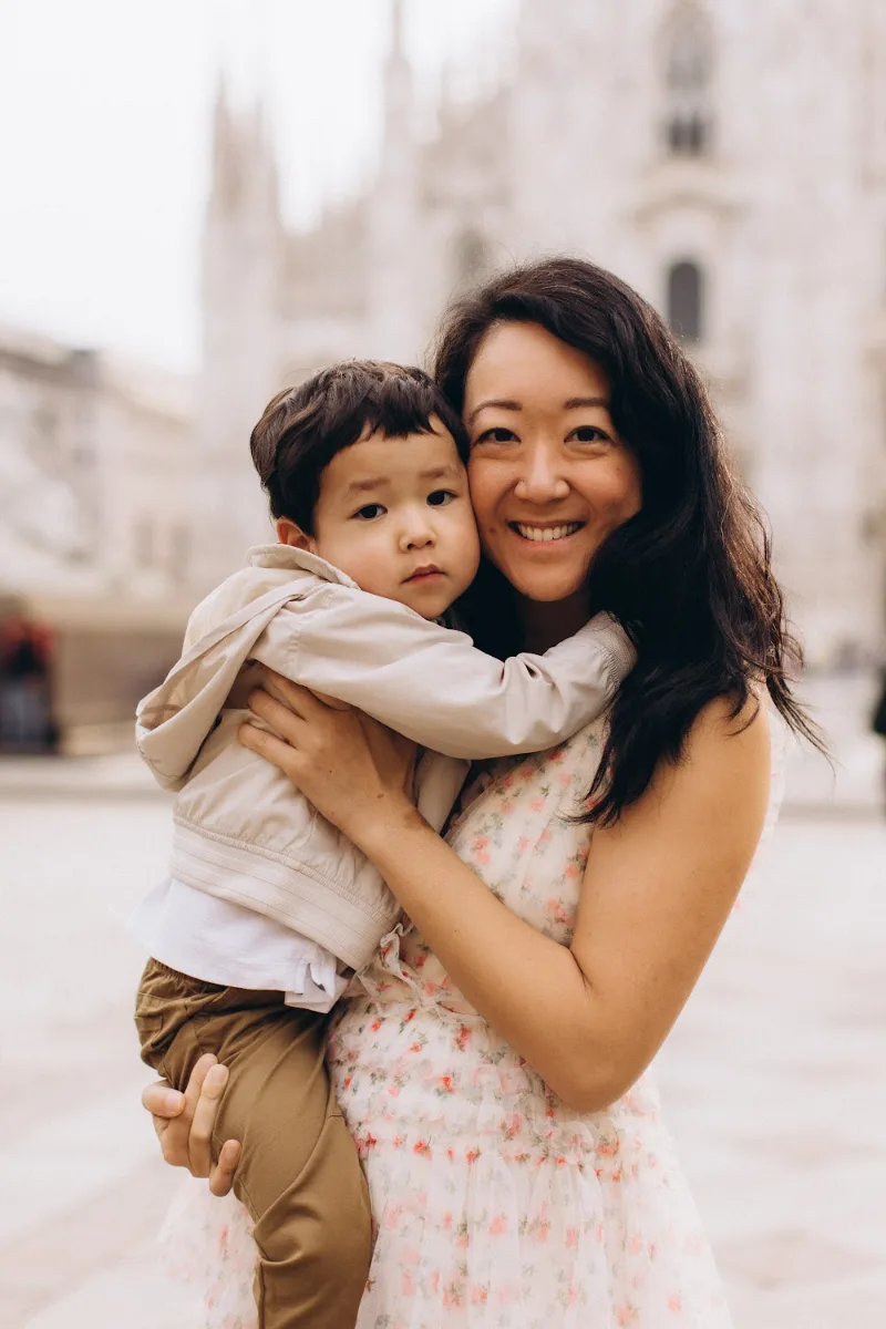 Mother hugging her little son and laughing in Piazza del Duomo, Milan
