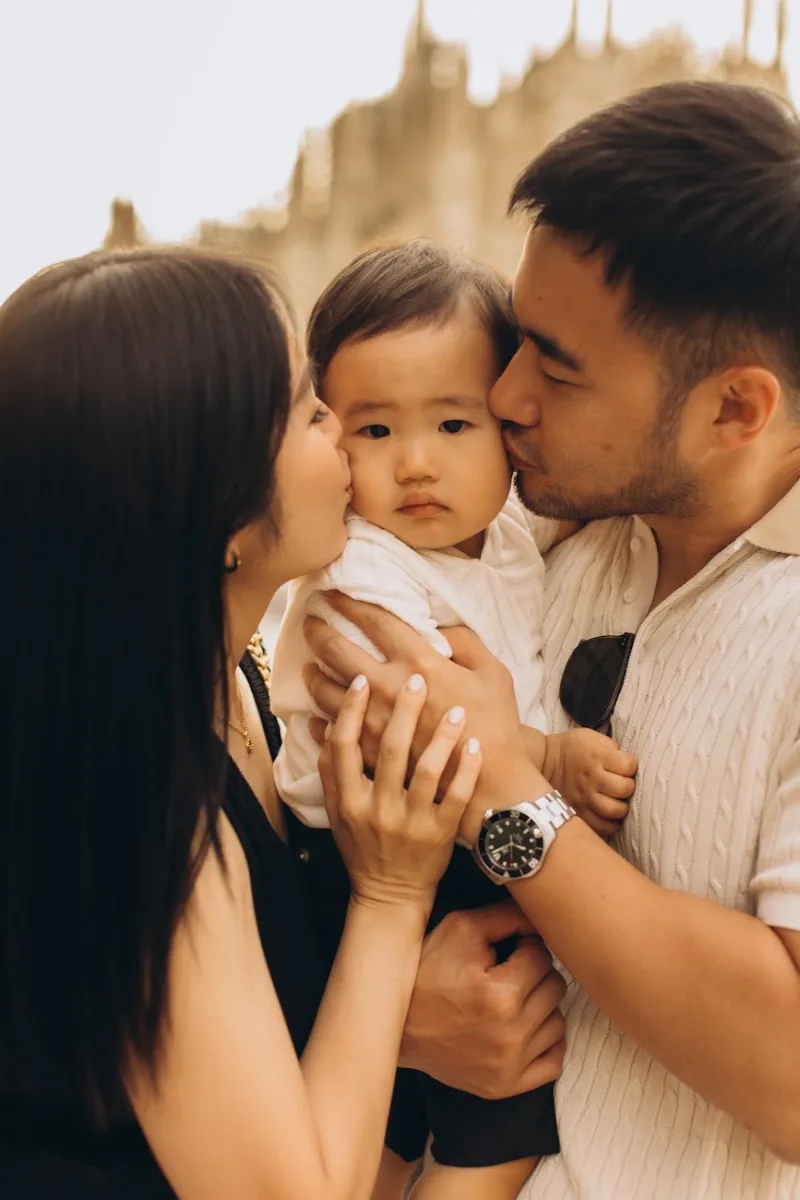 Parents kissing their baby’s cheeks in Milan