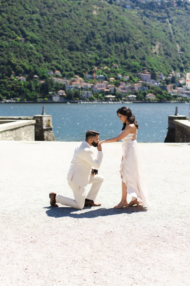 He kisses her hand right after she says yes on Lake Como