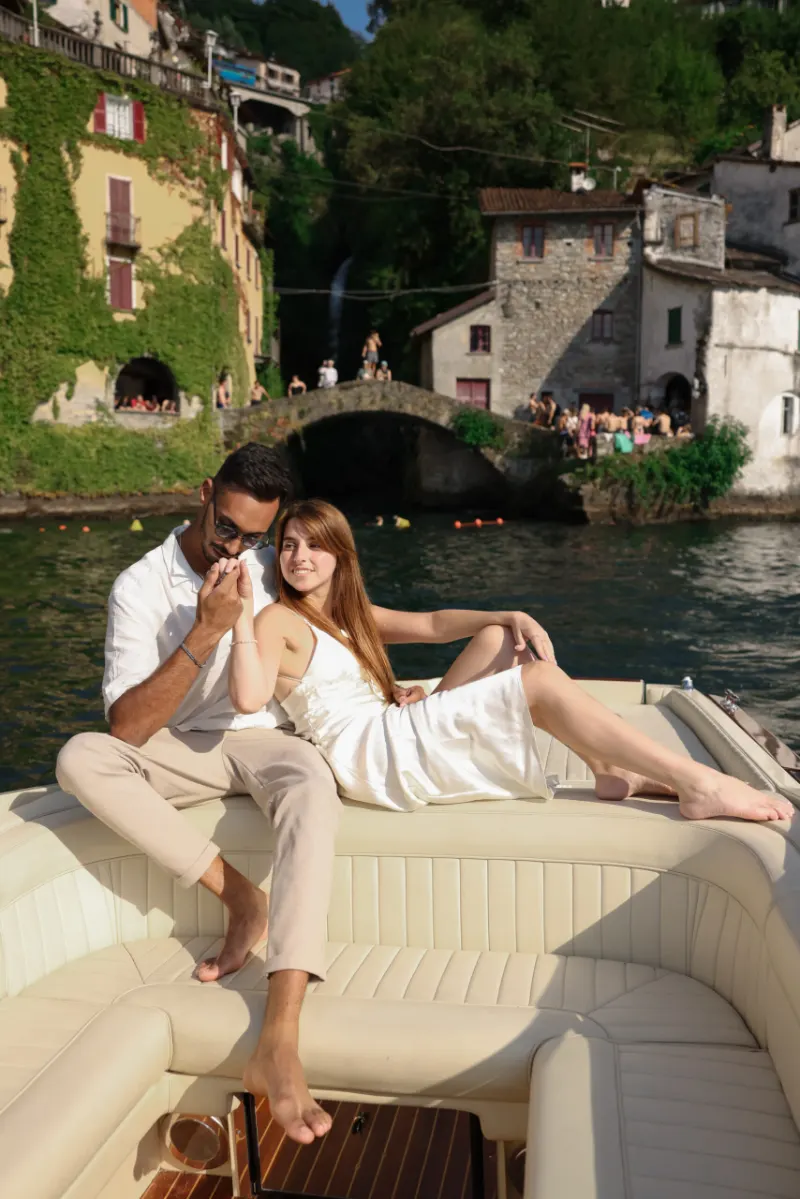 Couple on a wooden boat by the waterfall in Nesso, Lake Como