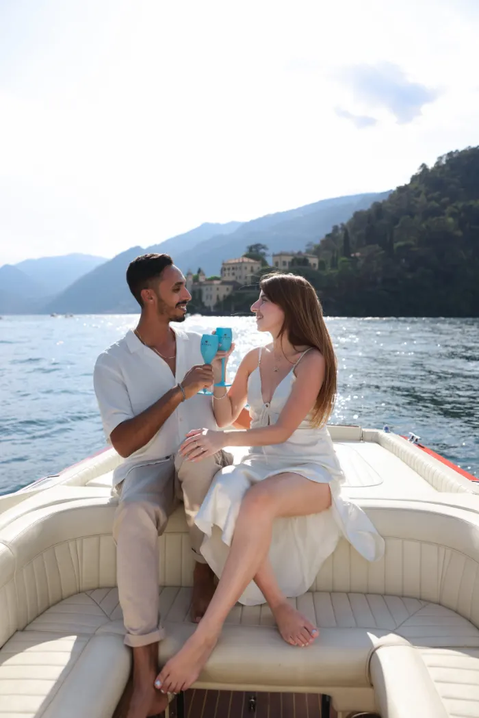 Couple toasting on a wooden boat after a proposal on Lake Como