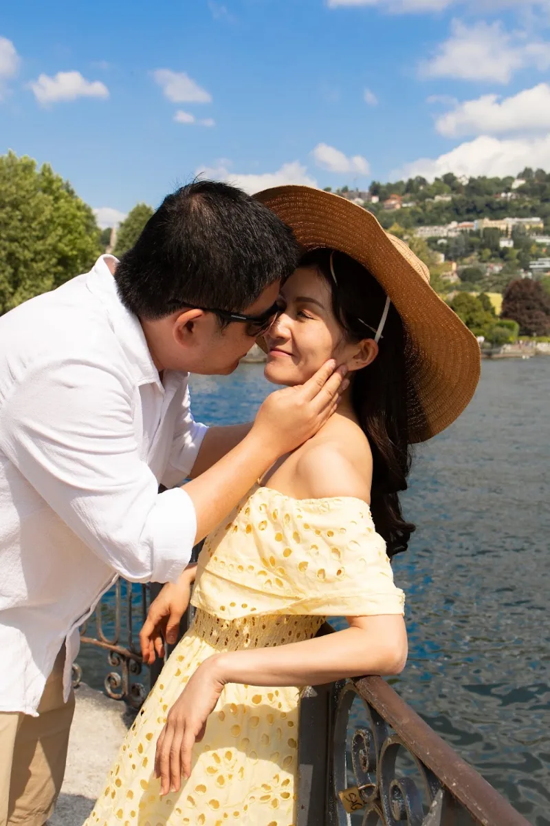 He kisses her cheek under a straw hat by the lake, Lake Como