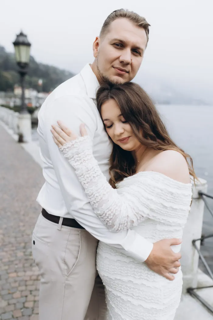 Expecting couple in a tender embrace on the Lake Como waterfront