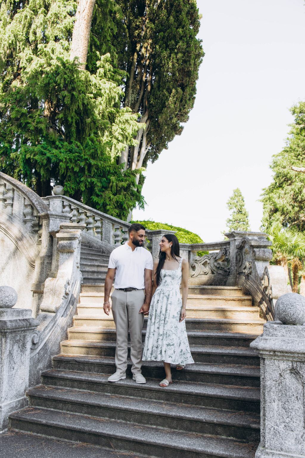 Couple holding hands on the monumental granite staircase of Parco Teresio Olivelli in Tremezzo, Lake Como, before a surprise proposal