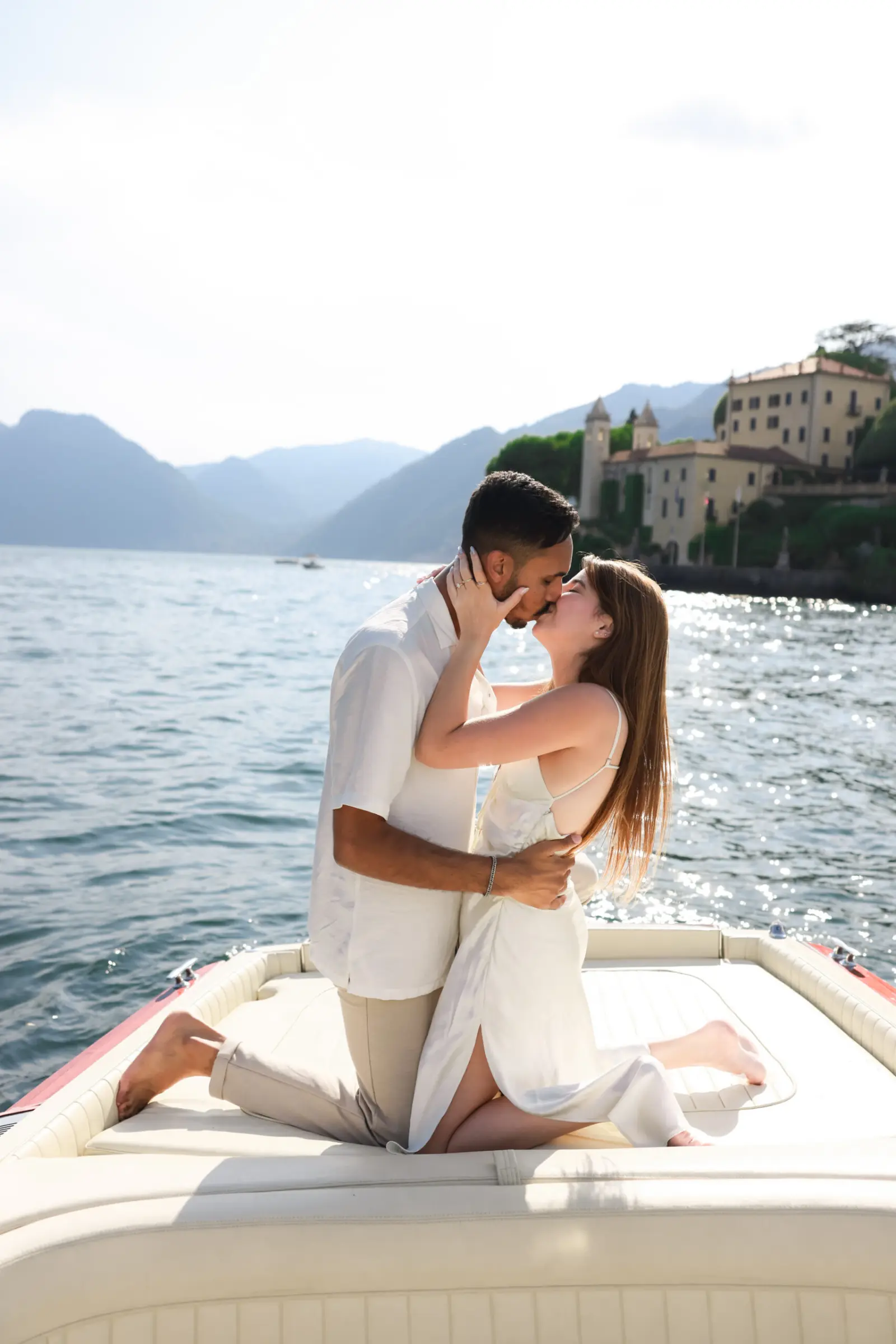 A newly engaged couple kisses on a boat on Lake Como