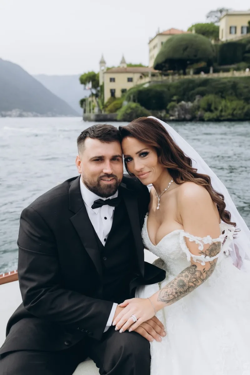 Bride and groom on a wooden boat in front of a lakeside villa, Lake Como