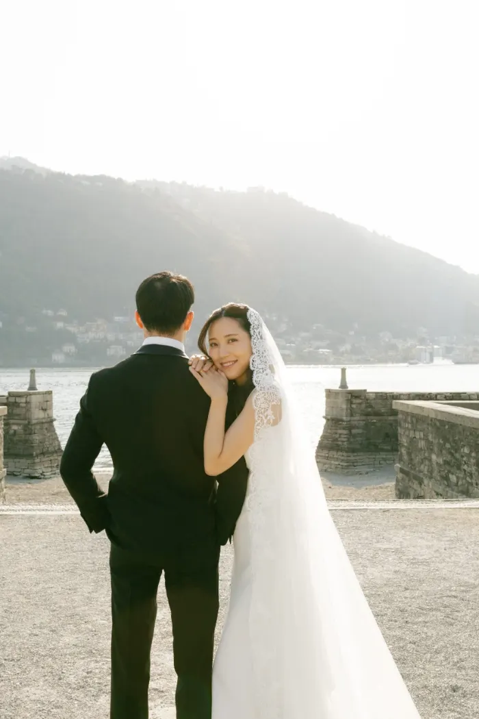 Bride smiling over the groom's shoulder by Lake Como