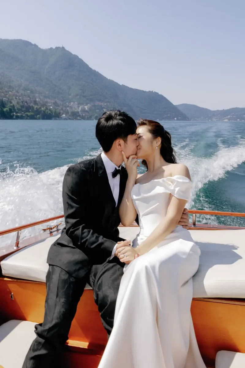 Bride and groom kissing in the stern of a wooden boat on Lake Como