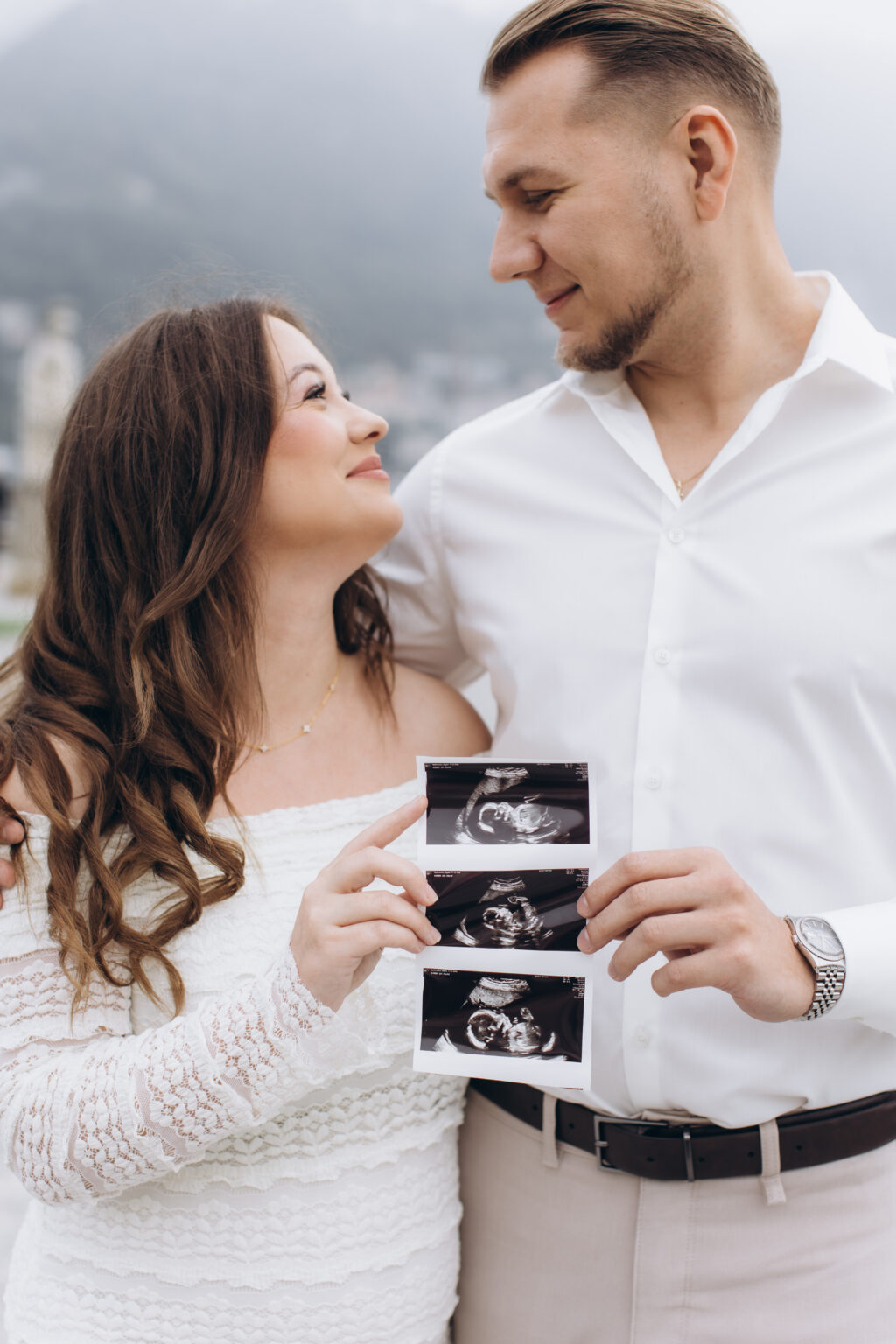 She holds a three-image ultrasound scan against him as they gaze at each other in the misty gardens of Villa Olmo, on Lake Como.