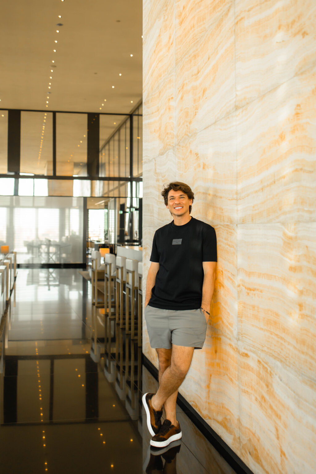 Her partner leans against a backlit onyx wall in a lounge at the Armani Hotel Milano.