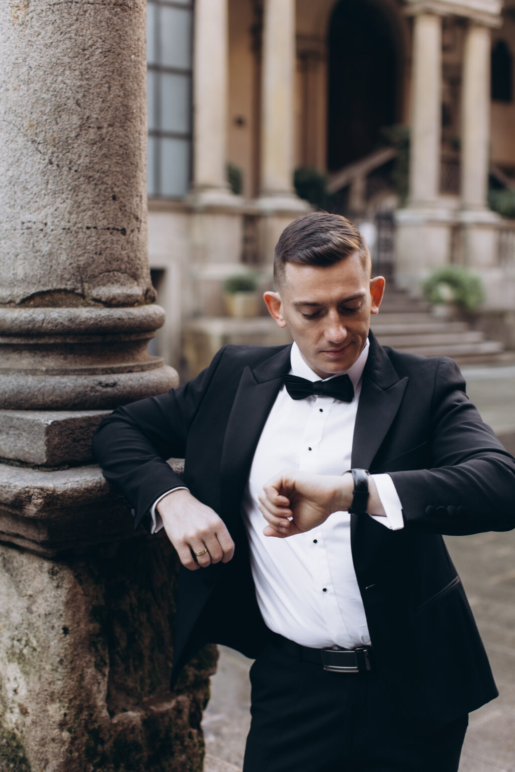 He checks his watch while leaning against a granite column in a historic brick-arcaded courtyard in central Milan.