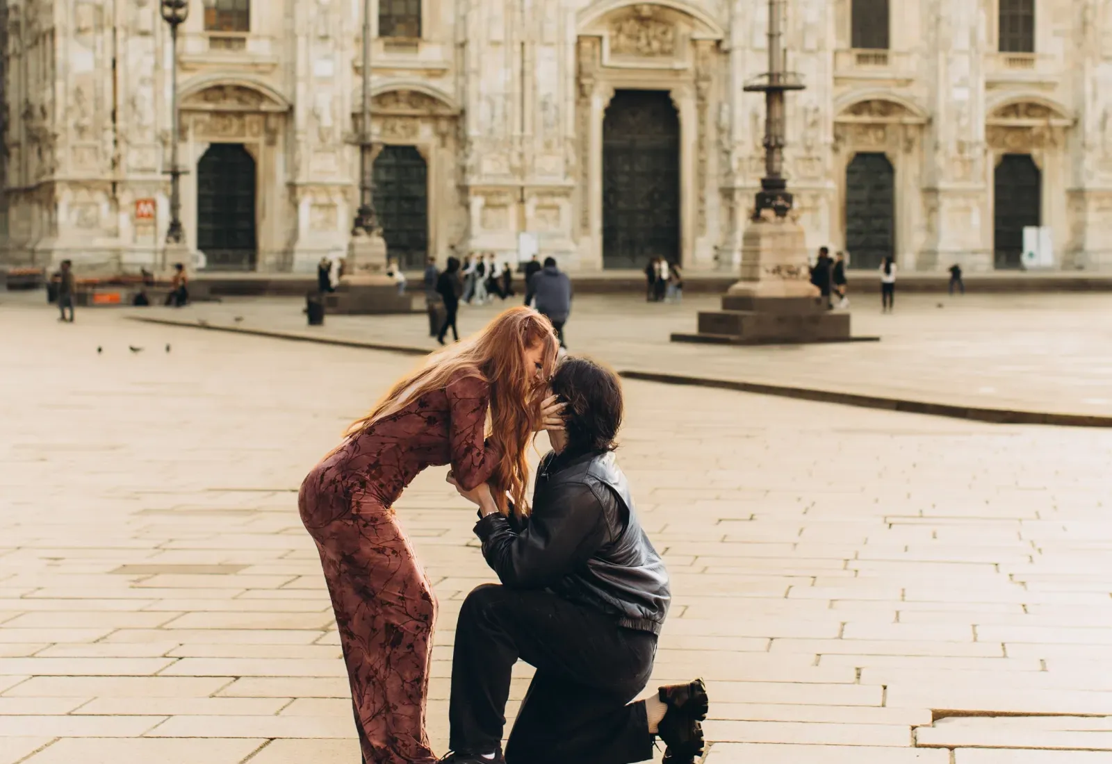 She hugs him as he kneels to propose in an empty Piazza del Duomo, Milan