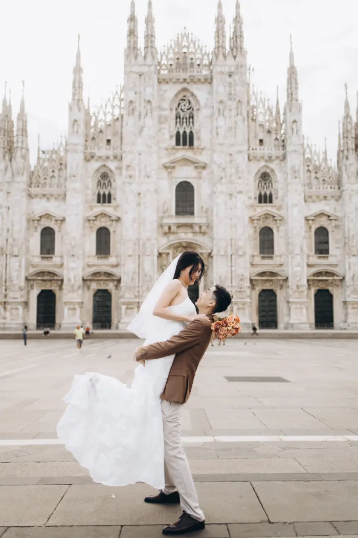 Groom carrying his bride in front of the Duomo in Milan