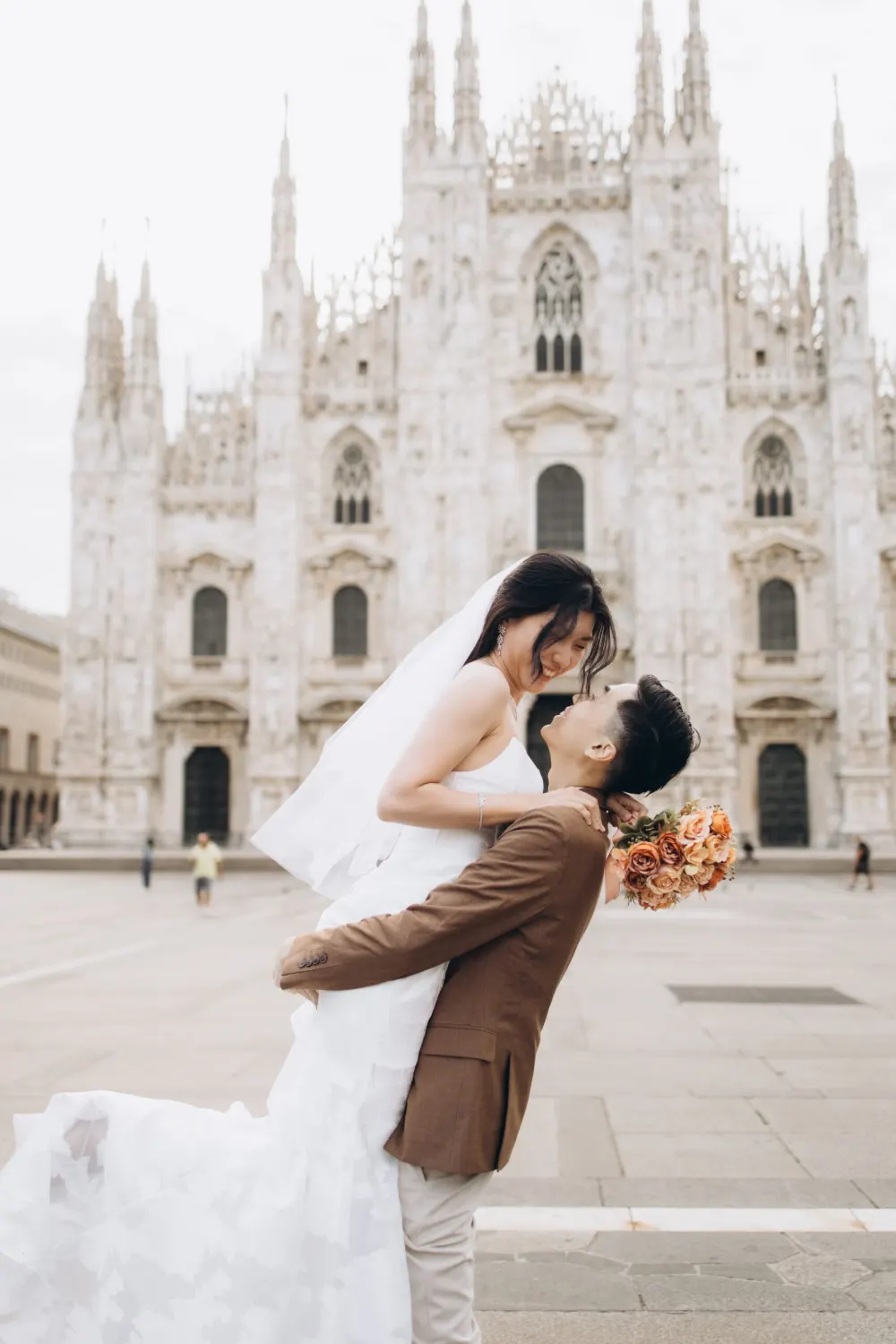 Groom lifting his bride in front of the Duomo in Milan