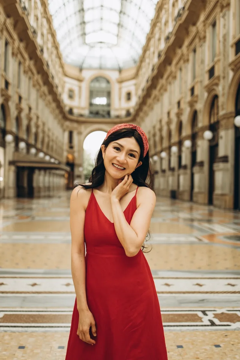 Woman in a red dress smiling in the empty Galleria Vittorio Emanuele II, Milan