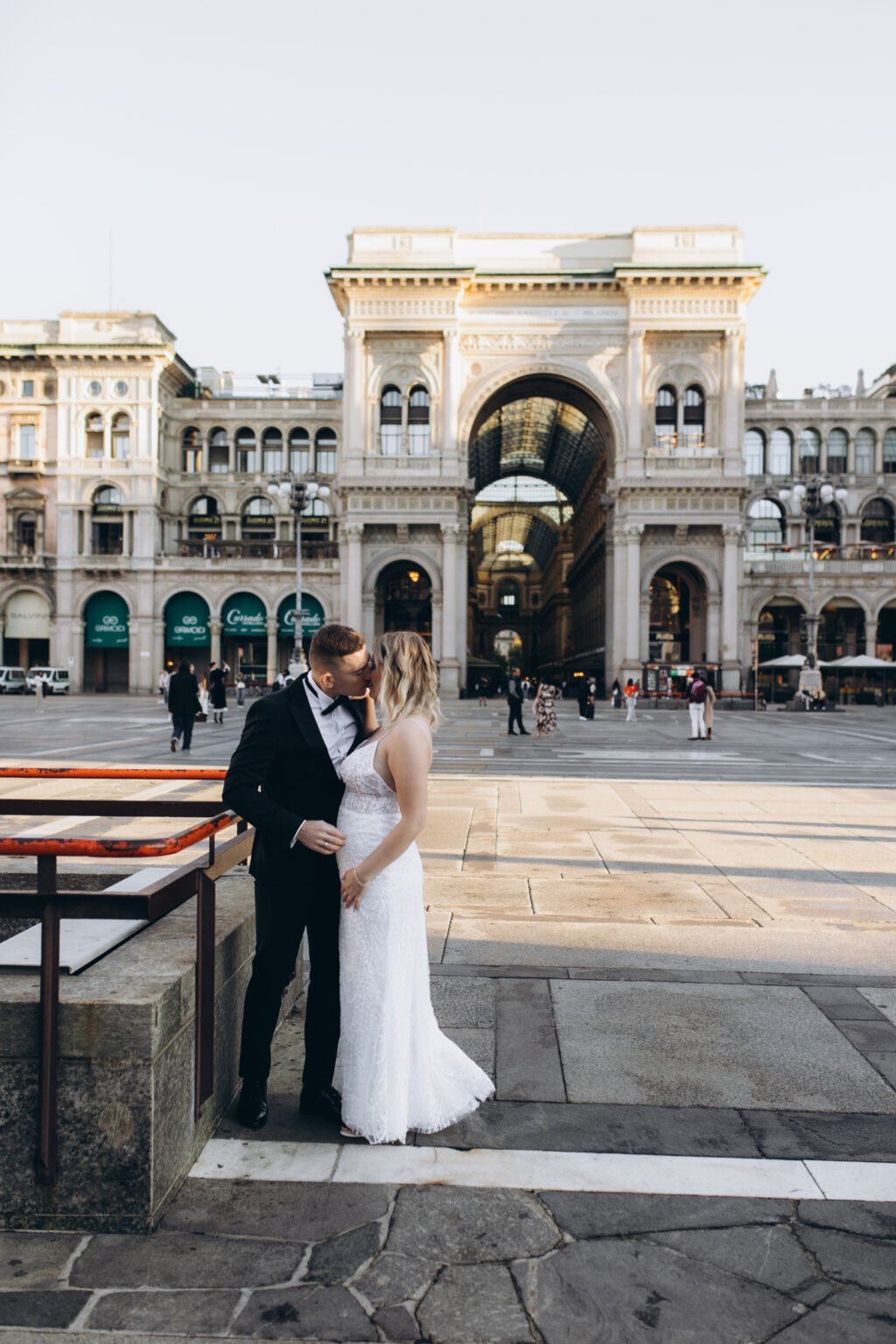 The couple kiss on Piazza del Duomo with the triumphal-arch entrance to the Galleria Vittorio Emanuele II behind them.