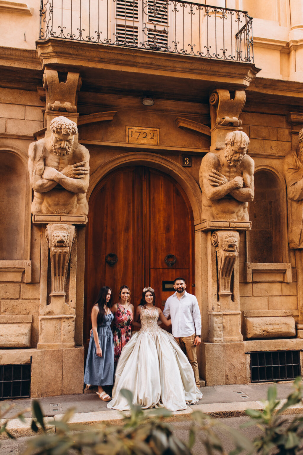 Quinceañera and her family, sister, mother, and father, gathered at the 1722 doorway of the Casa degli Omenoni in Milan.