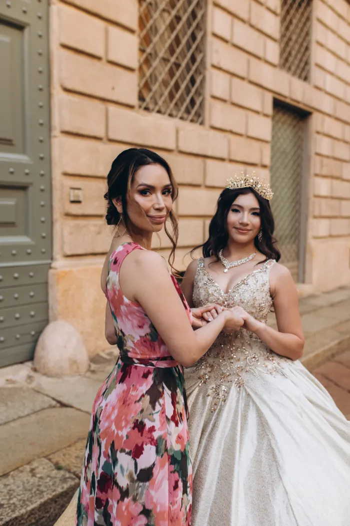 Mother and daughter standing side by side in a warm Milan street