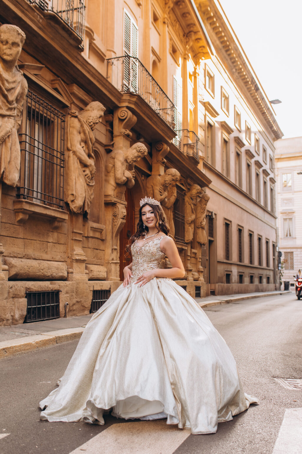 Quinceañera with her gown spread across the street below the carved giants of the Casa degli Omenoni in Milan.