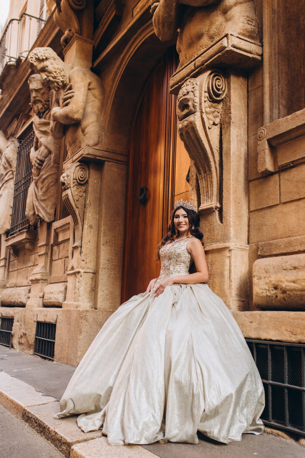 Quinceañera seated at the carved wooden portal of the Casa degli Omenoni, framed by Renaissance telamones in Milan.