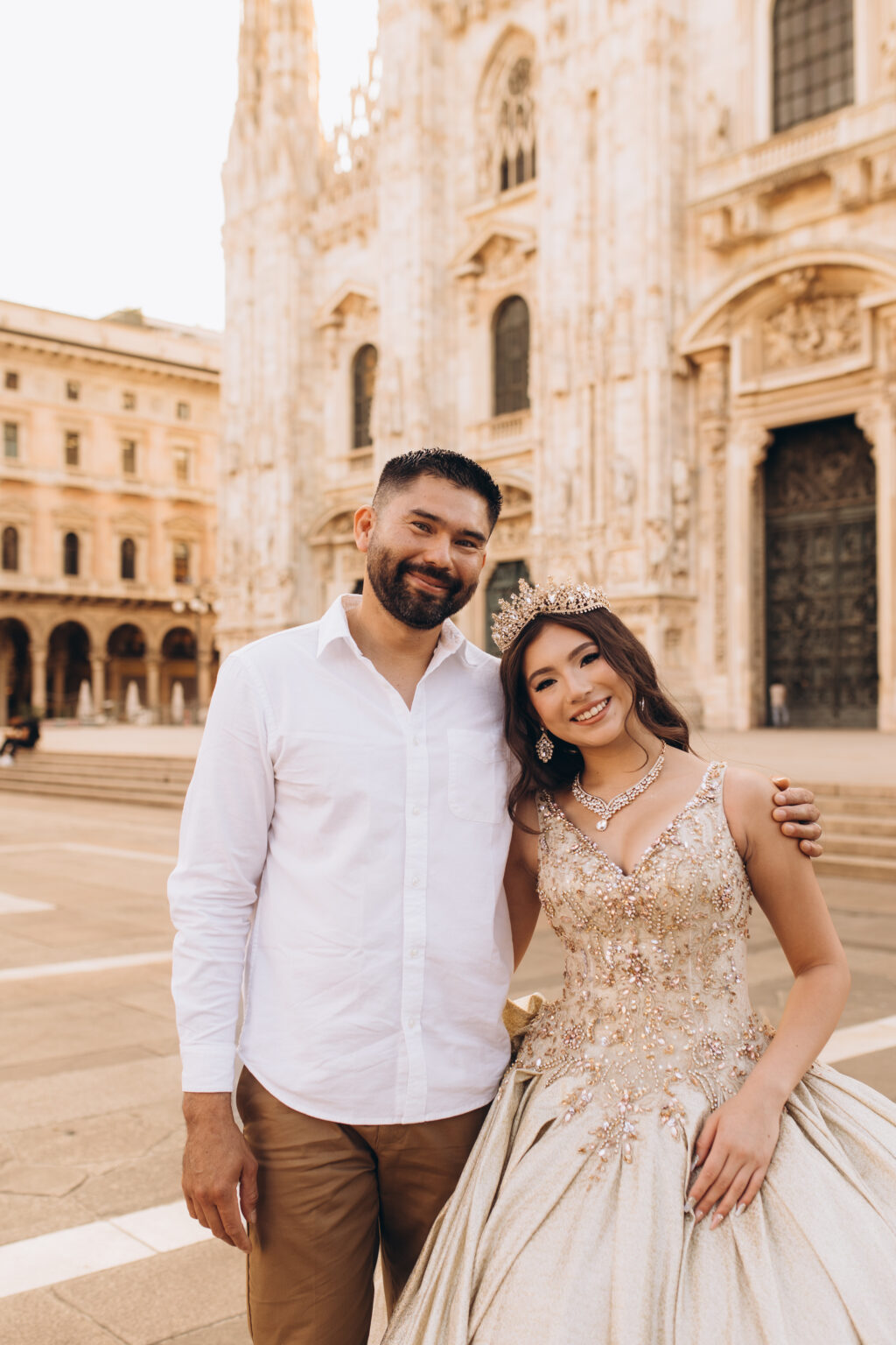 Quinceañera and her father stand close before the marble facade of the Milan Cathedral in Piazza del Duomo.
