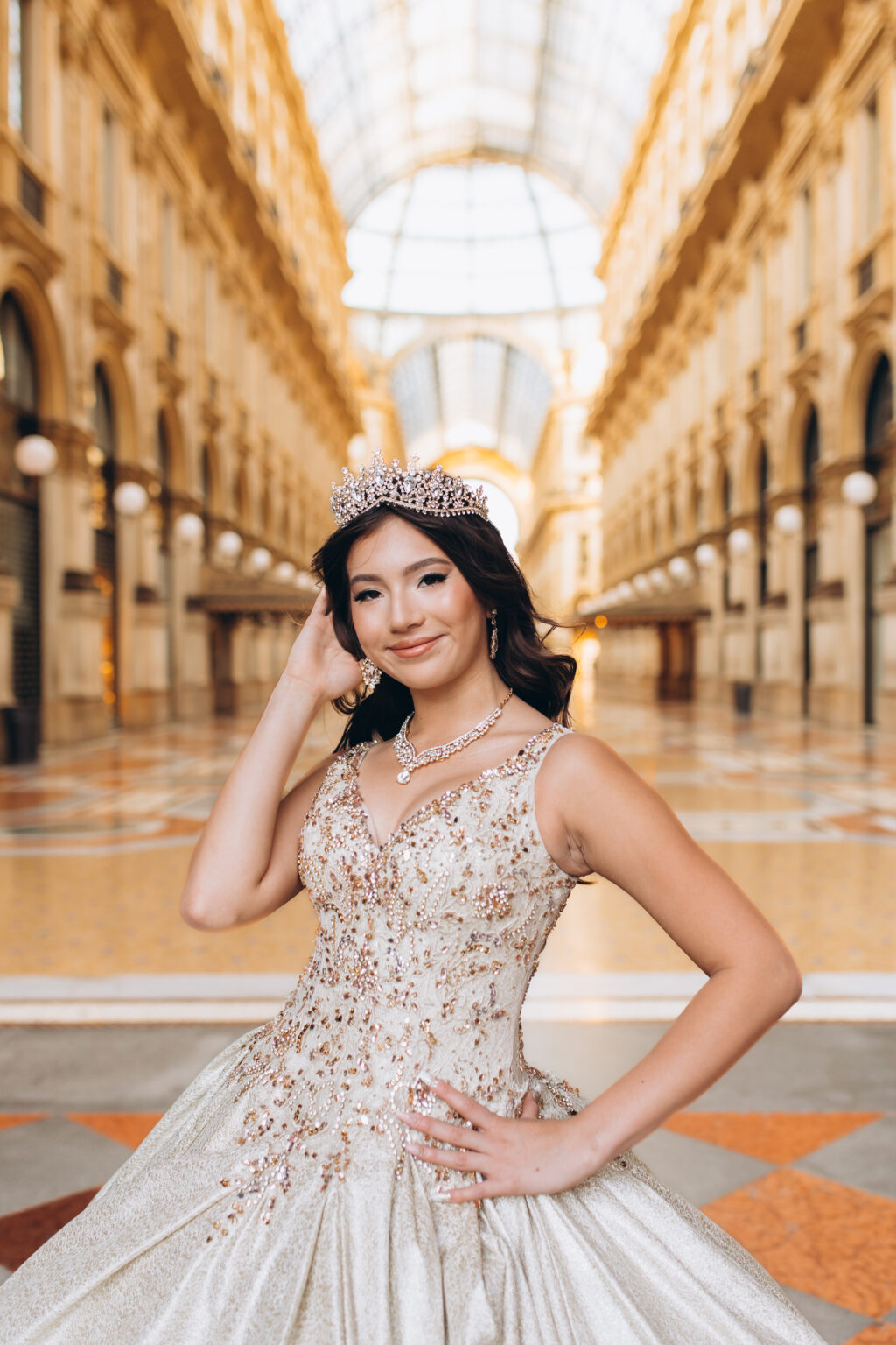 Close portrait of a smiling quinceañera wearing a crystal crown and necklace in the Galleria Vittorio Emanuele II, one of many quinceañera portraits in Milan.
