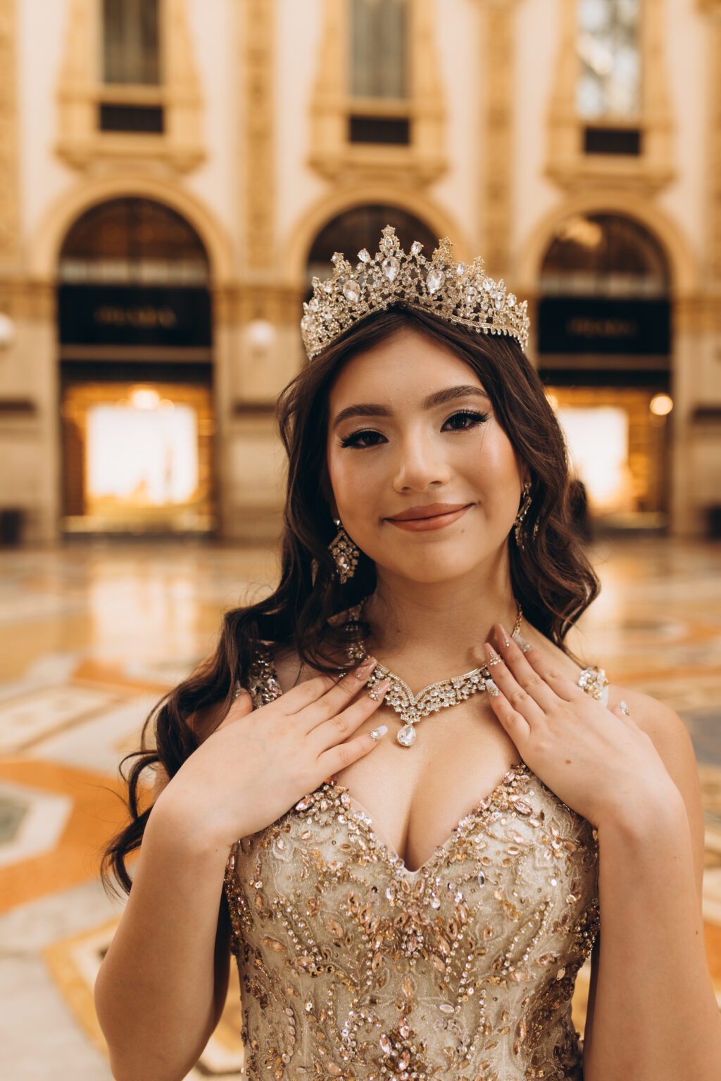 Close portrait of a crowned quinceañera touching her necklace inside the Galleria Vittorio Emanuele II in Milan.