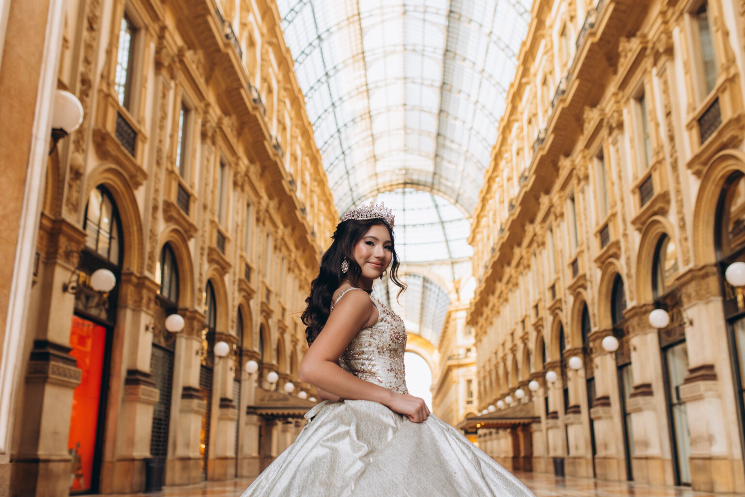 Low wide view of a quinceañera turning beneath the great glass dome of the Galleria Vittorio Emanuele II in Milan.