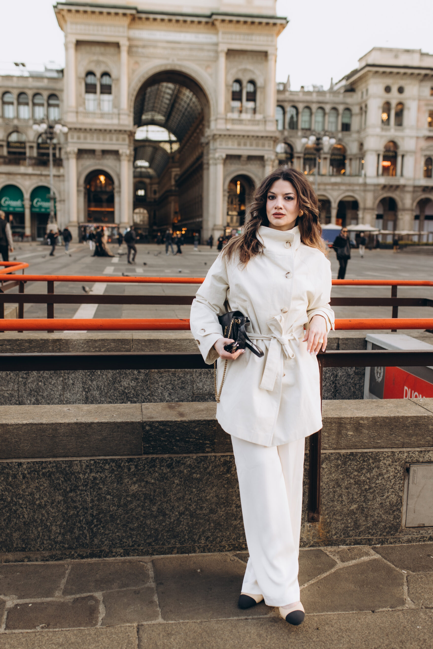 Winter Portrait at Piazza del Duomo by the Galleria, Milan A woman in a white outfit poses in Piazza del Duomo with the entrance to Galleria Vittorio Emanuele II behind her in Milan