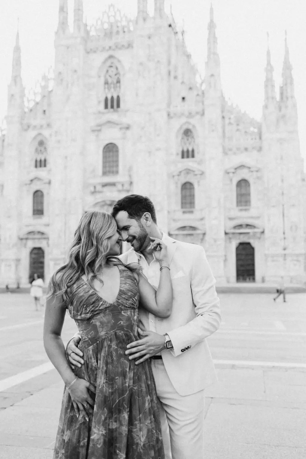 Black-and-white portrait of the couple forehead to forehead and smiling, his arm around her waist, with the Duomo behind.
