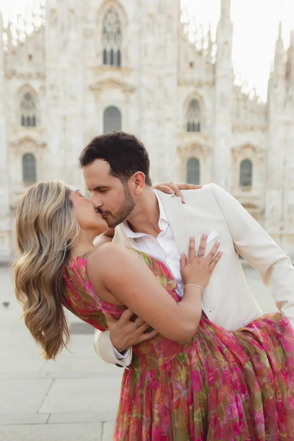 He dips her back into a kiss, her hand on his cream lapel, the Duomo's rose window softly blurred above them.