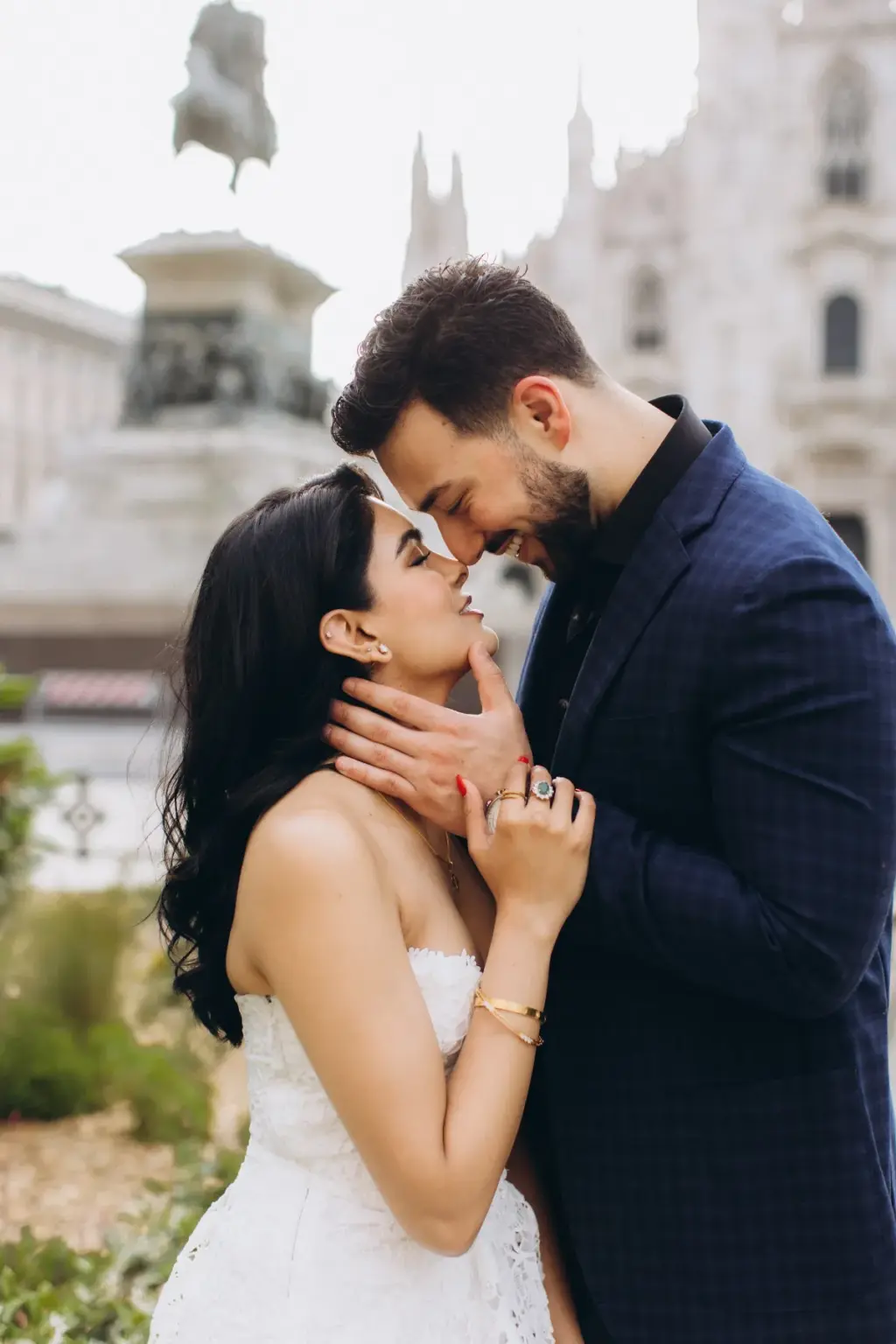 In colour, he holds her face with both hands as she leans in with eyes closed, the Duomo and a bronze rider statue blurred behind.