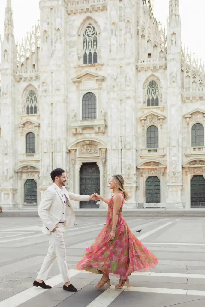 Holding hands at arm's length, the couple dances on the Duomo square as her pink floral dress swirls around her ankles.