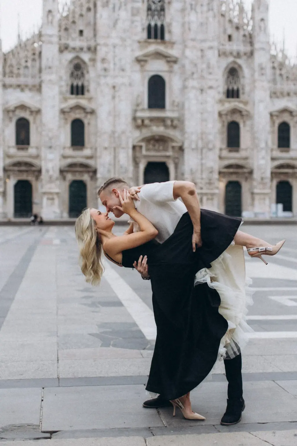 He dips her low on the Duomo square as she kicks up one nude heel, her black skirt and white tulle layers spilling down.