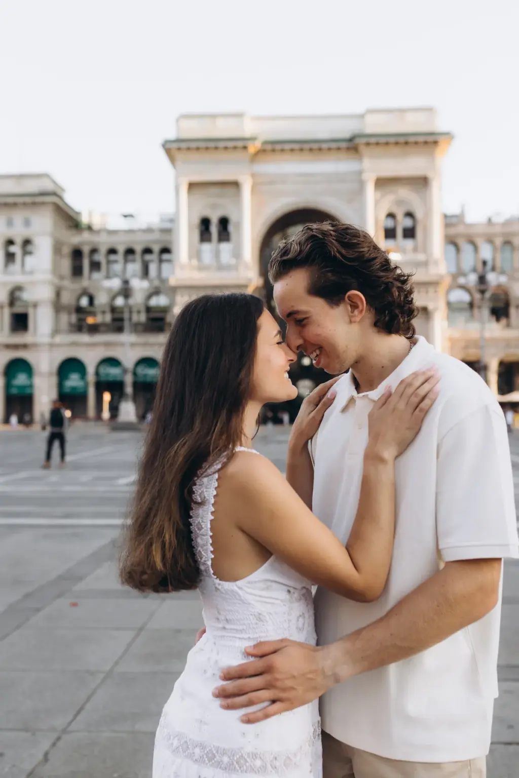 Smiling with closed eyes, a man touches foreheads with his partner in front of the triumphal arch entrance of the Galleria.